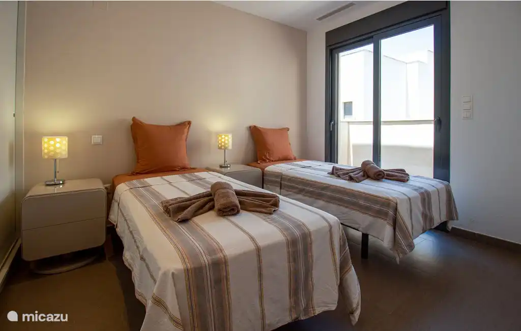 Slaapkamer met twee eenpersoonsbedden en toegang tot het dakterras